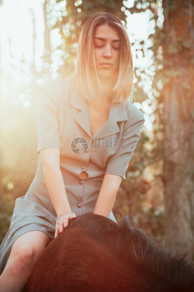 动物关心女美丽的年轻子骑着她的棕色马穿着衣服图片