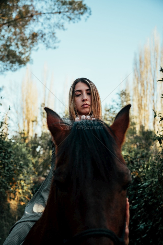 农村美丽的年轻女子骑着她的棕色马穿着衣服吸引人的乐趣图片