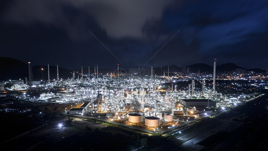商业汽油夜间在泰国炼油区工厂使用不锈油管的轮和气罐车灯光模糊蓝天背景空中观察图片