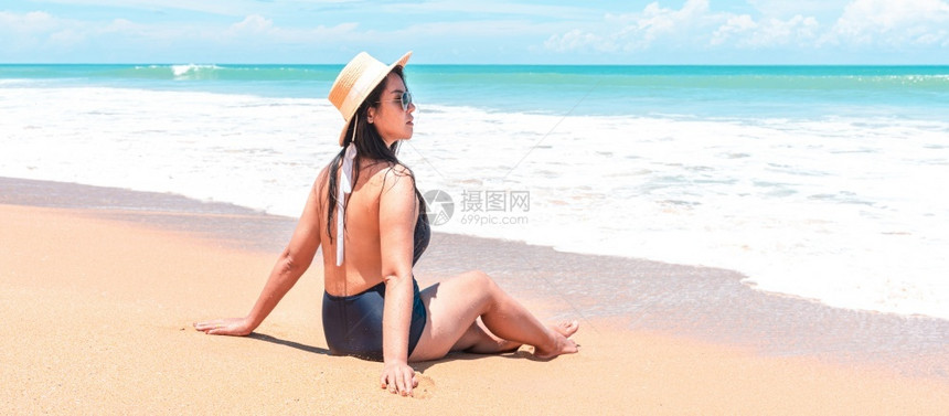 尽管身穿泳衣和草帽的亚洲旅行者妇女背视坐在海面喷水中看洋蓝色地平线同时在节日旅行中放松阿桑海滨图片