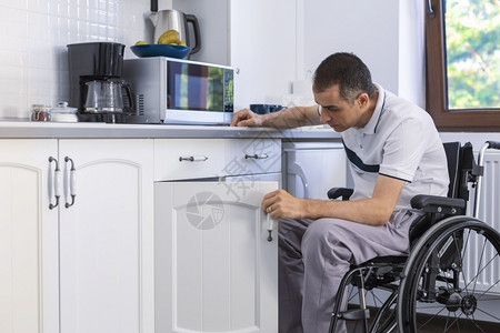 重点白种人无能力青少年残疾人坐在轮椅上厨房看他的脸部图片