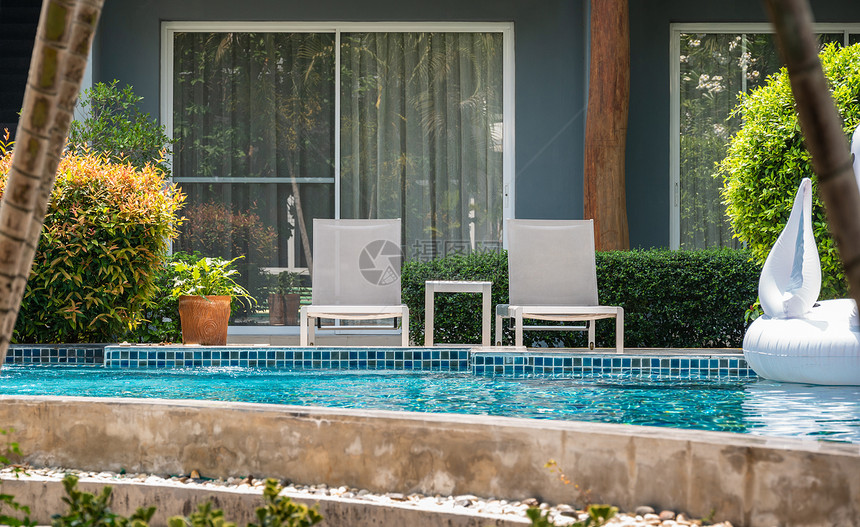 岩石在度假旅行休闲店的户外游泳池旁两张甲板椅子和桌边采取绿色图片