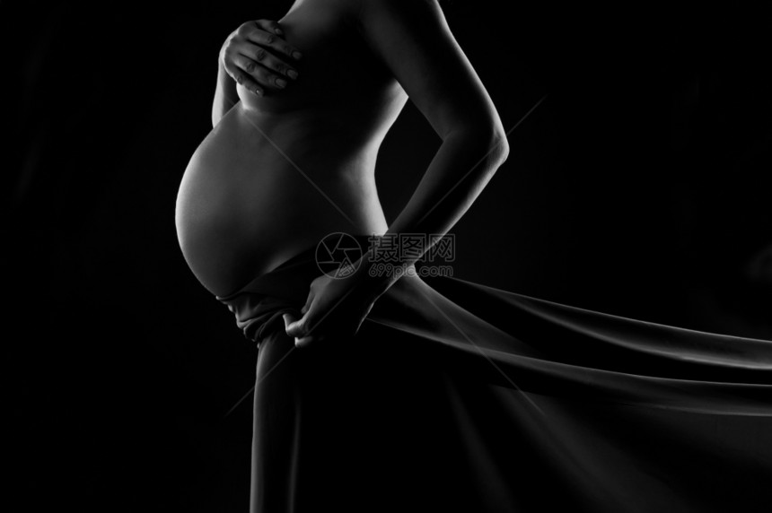 女士健康纺织品身穿丝纱的孕妇展示她腹部黑色和白工作室拍摄在黑色背景上图片