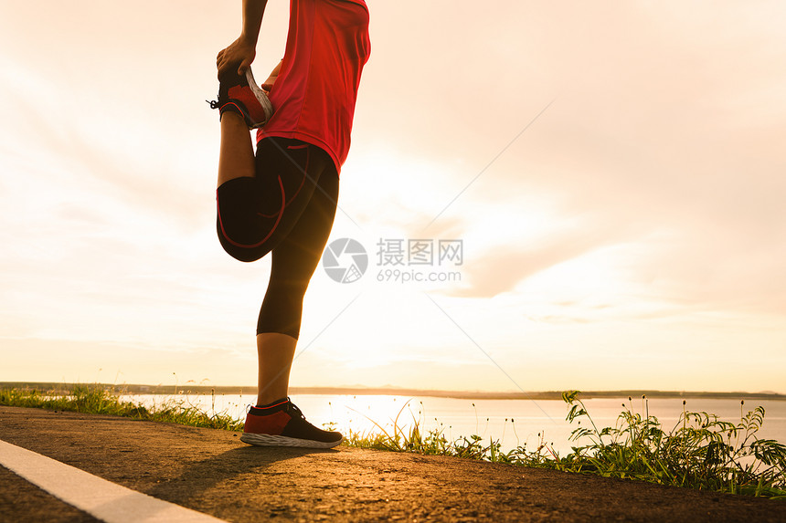 健康妇女伸展腿肌肉准备日落的足迹跑马拉松赛者图片