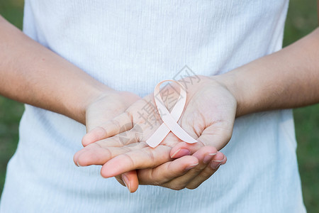 手握桃色丝带预防癌症概念背景图片