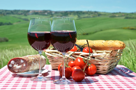 爬坡道红葡萄酒面包和西红柿在彩布上与意大利的托斯卡纳风景对比柏酒精图片