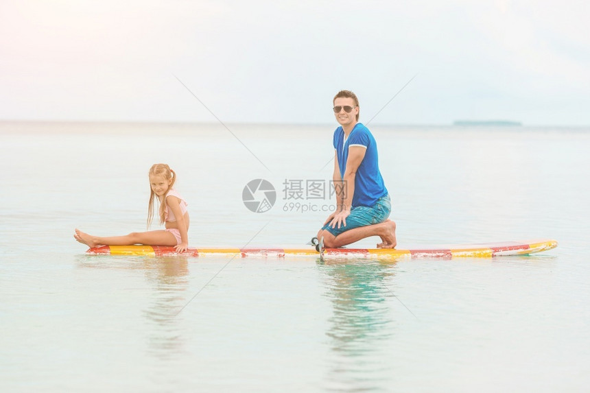 冲浪者父亲和孩子的家庭有乐趣一起在大海划船暑假期间爸和孩子在冲浪板上玩耍训练登机图片