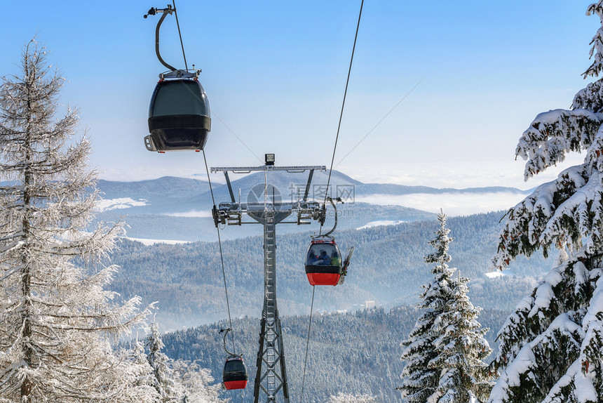 Gondola小木屋在森林上滑雪胜地的度假升起以阳光明媚的日天化下雪山为背景旅游采取舱图片