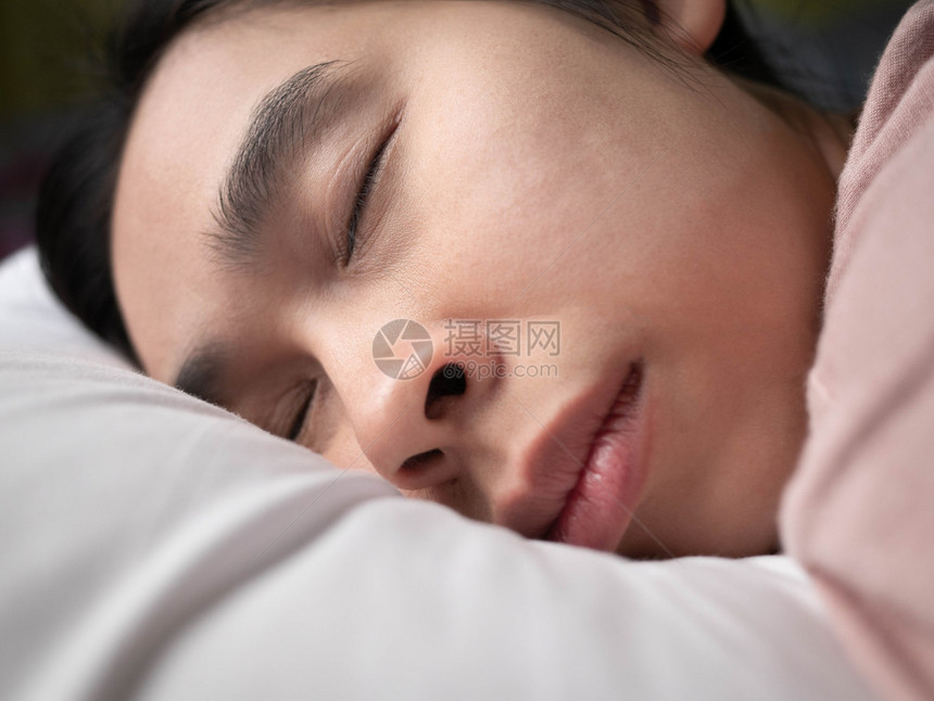 成人紧贴近面脸的亚洲年轻女子睡得安稳地躺在床上拥抱柔软的白色枕头松弛早晨图片