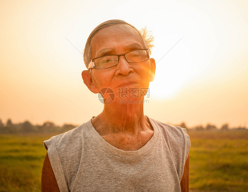 训练70年代亚洲高长男子在农村保健概念的一个领域日落背景上慢跑的亚洲高级男子草图片