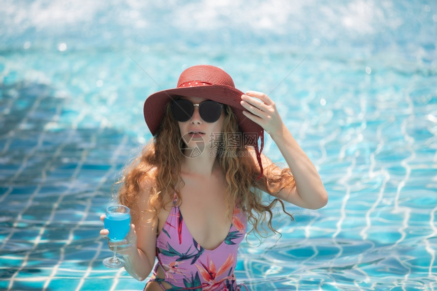 水池朋友们采取女人穿比基尼和喝鸡尾酒在热暑假游泳池图片