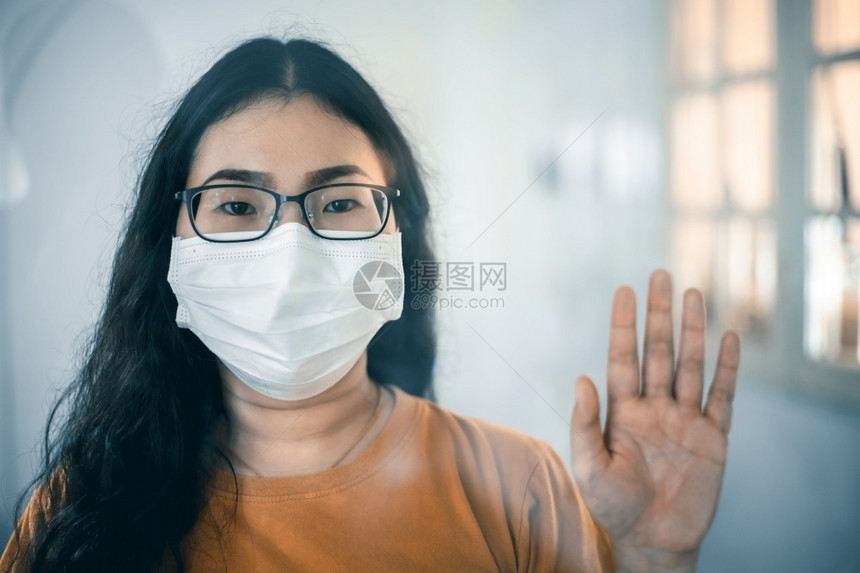 药物裙子女士以橙色衣服穿戴保护卫生面罩的亚洲女肖像穿着橘色礼服手拿着保护套做停止势同时在咨询过程中观看照相机COVID19概念图片