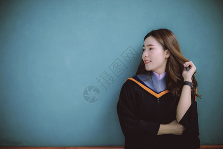 套装老师穿着大学毕业西装的女子站在清晰蓝墙上带着快乐的情绪微笑着容的脸上亚洲人广阔高清图片素材