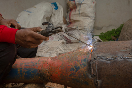 技能的工程面具焊接机正在施工地焊接金属管道图片