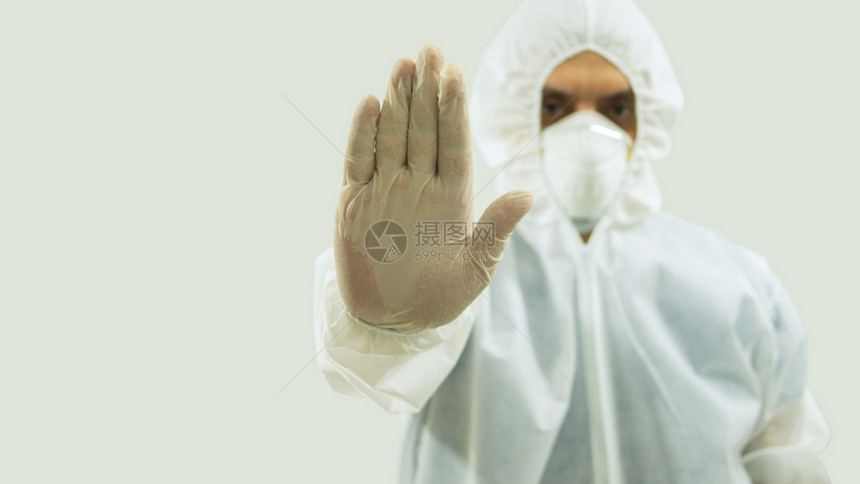 男制造戴着面具和生物防护服的医正面图手臂向前伸出右手张开在白色背景上做一个停车标志手套图片