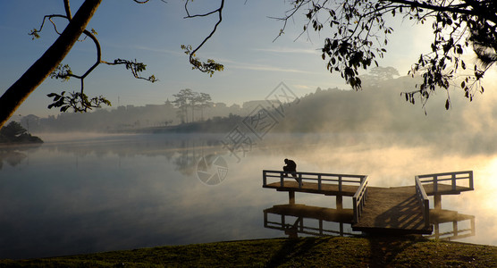 城市亚洲人日出大拉特市令人惊异的地貌清晨在大拉特市的景色中人月光下在小桥上做运动在湖面水上反射池塘中的雾蒸发为越南旅行的浪漫场景背景图片