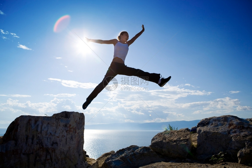 季节仅有的正在做快乐年轻女士在夏天从蓝的岩石上自由跳下做一个巨大的自由跳跃图片