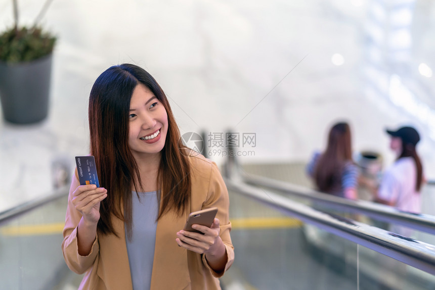 手指在线的利用带有智能手机的信用卡在百货商店网上购物技术钱包和在线付款概念的亚洲妇女肖像式信用卡和智能移动电话进行网上购物转移图片