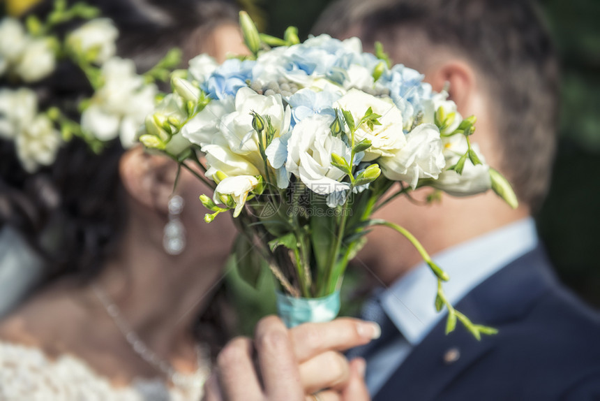 男幸福新郎手上漂亮的婚礼花束在新娘手上接吻快乐的图片