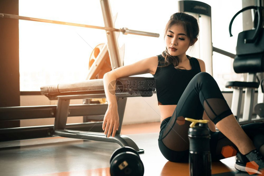 亚洲青年女子在健身和体育俱乐部中心休息配备设和哑铃运动强力训练概念美与健康主题具有健身和体育俱乐部背景美丽运动员福利图片