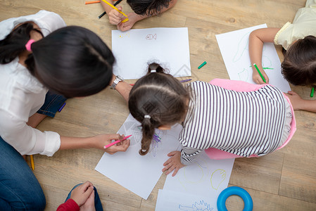 幼儿园小朋友趴在地上一起画画女学生高清图片素材