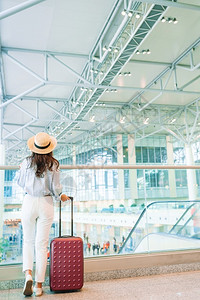 国际机场带行李的年轻女子国际机场带行李的戴帽子年轻女到达手提箱飞图片