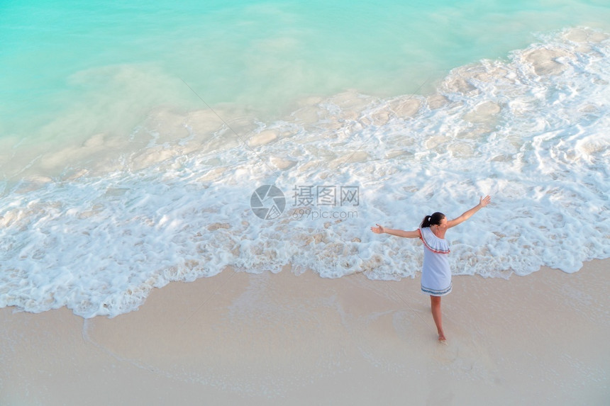 白色的海滩上美丽的女孩在浅水海滩上从面看浅水快乐女孩在海滩玩得很开心在浅水女士图片