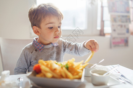 小男孩吃薯条在吃食物的小男孩背景