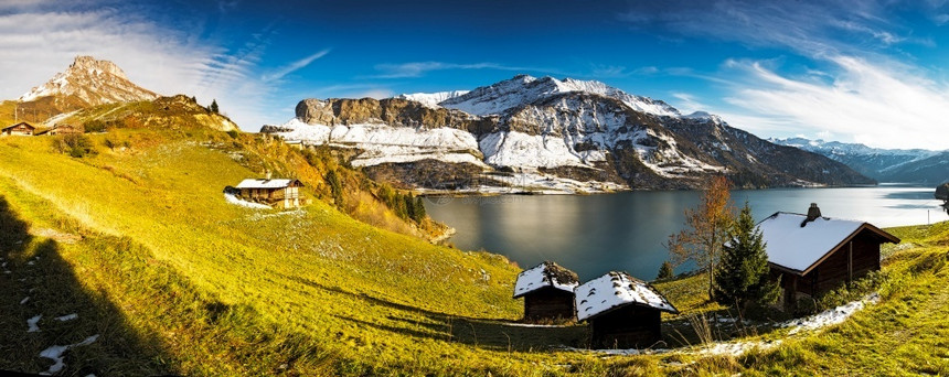 安宁反射在高山的湖中雪覆盖着高山湖泊上的峰和草地小屋徒步旅行者图片