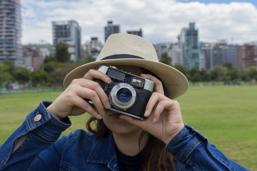 愉快乐趣阳光明媚的早晨美丽西班牙裔女子戴着帽在公园中央用旧相机拍照复古的图片