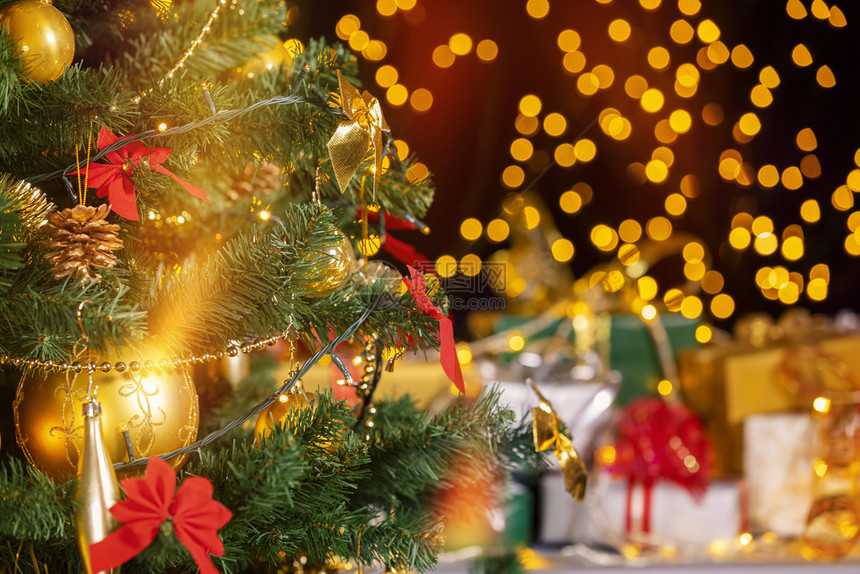 圣诞节树下面堆满的礼品箱对着微粒灯光在树下放许多圣诞礼物以黄色地球为焦点选择魔法金的图片