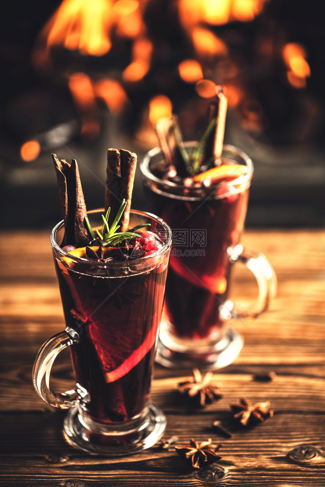 五香深思熟虑快乐的在火炉灾背景下在圣诞节假日传统冬季饮酒时木制桌上的边装有玻璃杯中调味品的混合葡萄酒图片