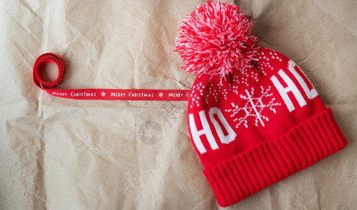 12月25号礼物12月5日红丝带上印有圣诞快乐和红色帽子在工艺纸上展开圣诞节概念12日红丝带上印有圣诞快乐和红帽子一种白色的背景