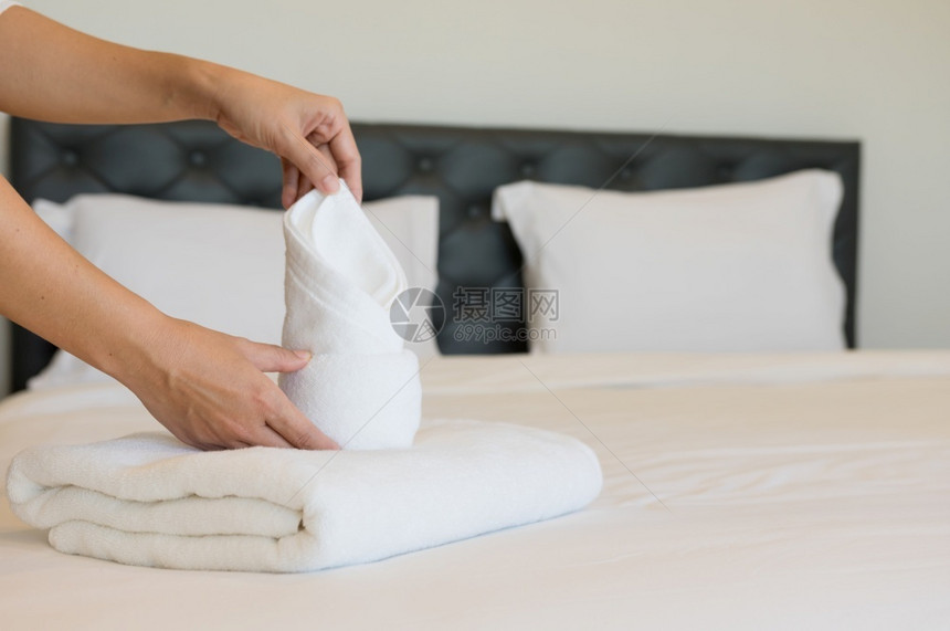 年轻的旅馆女青把软毛巾床铺和放在一家旅馆清洁工身上放在床干净的白毯子早卧室有枕头软毛巾清洁器女佣曾是图片