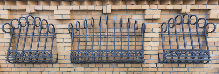 砖瓦的栅栏装饰用一个伪造的卷铁镀板制拉提层和砖墙树叶安全华丽的图片