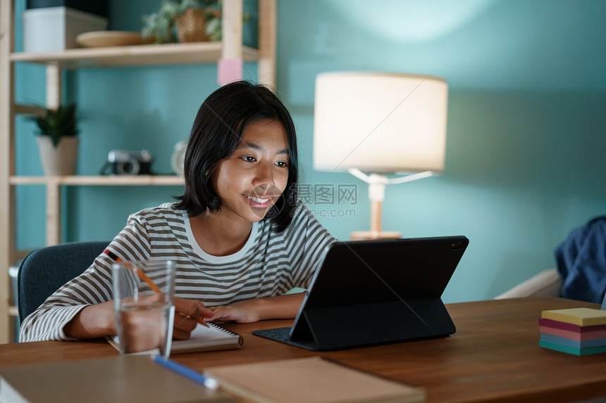 在家工作沟通上学的亚裔女孩做功课晚上和在平板电脑办公桌上的教师一起在线学习坐着图片