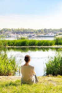 安详合身一个女人在冥想坐草地上河前面的清晨就在日出之后早晨平静的高清图片素材