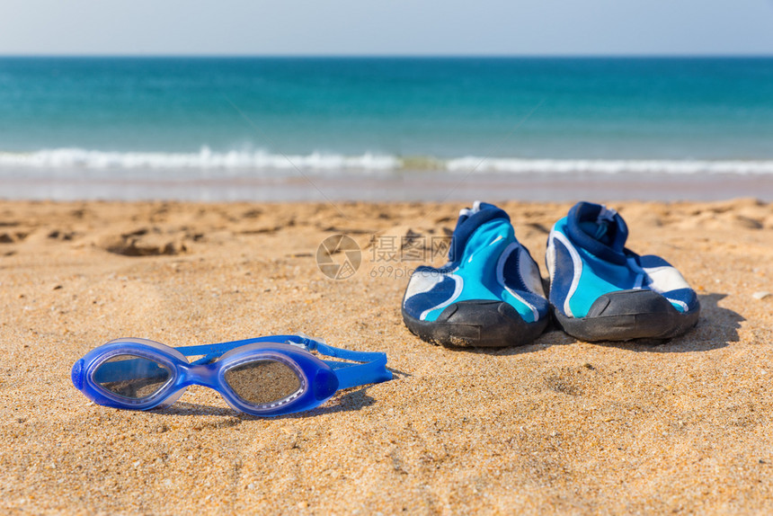 季节休闲的晴天蓝色游泳护目镜和水鞋停在海滨岸图片