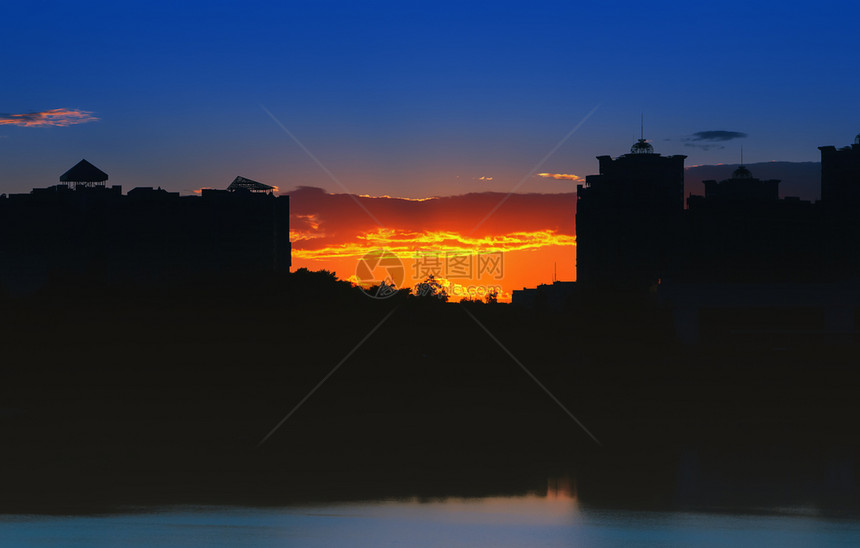 剪影黑色的夜间城市风景在日落时湖夜市风景中反映的橙色日落背景下高楼层的轮光阴影阳图片