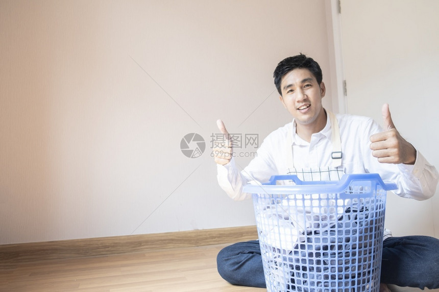 做家庭作业的亚洲男子丈夫他正在准备篮子中的衣物用洗机服为家里的庭团聚提供各种生活方式服务机器在职的服装图片