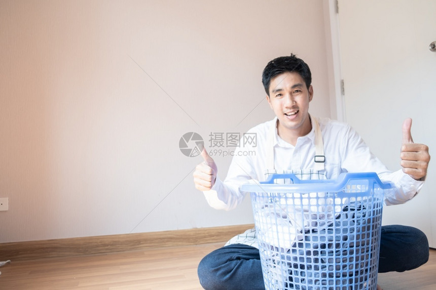 做家庭作业的亚洲男子丈夫他正在准备篮子中的衣物用洗机服为家里的庭团聚提供各种生活方式服务男人纺织品屋图片