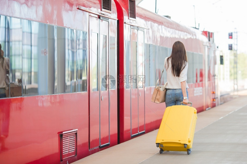 铁路在平台上携带行李的年轻女子等待着气压表情的回视妇女在火车站坐时背着袋子看女人表示移动图片