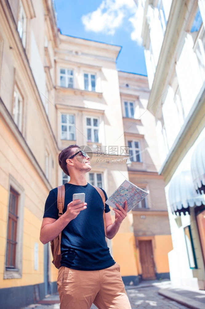 历史的地标维也纳街上带电话吉德和城市的青年男子旅游者在欧洲街上带城市和背包的黑人男孩看着欧洲城市东图片