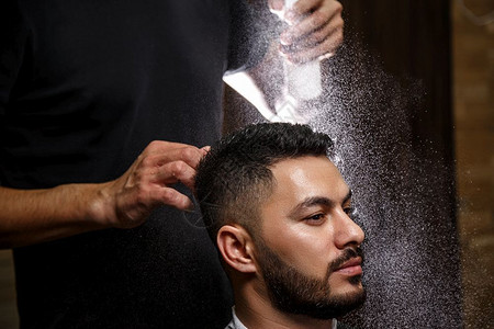 技能一种身着黑衣服的理发师正在给坐理发店扶椅上的时髦黑头发男子做型设计阳刚之气造型高清图片素材