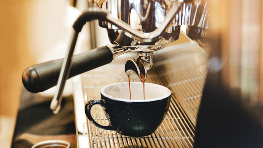 光滑的浓缩咖啡机冲泡倒入店的玻璃杯中浓缩咖啡从机中倒出热的咖啡因图片