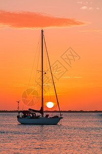 海洋一只帆船在橙色日落的海上航行支撑暮图片