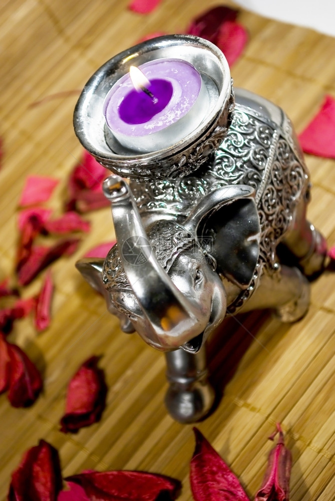 放松银象雕像上面有小紫蜡烛和红鲜花在木质纹身上象征紫色的图片