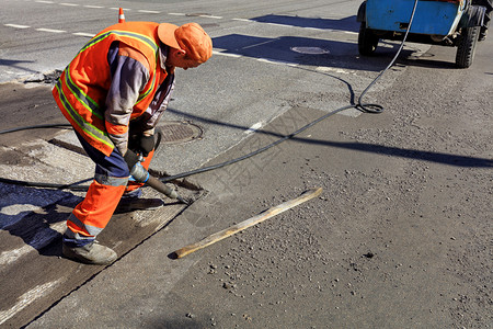 施工现场道路维修人在施期间用气动手提钻清除旧沥青工人在道路施期间用气动手提钻清除部分沥青铺外部乌克兰高清图片素材