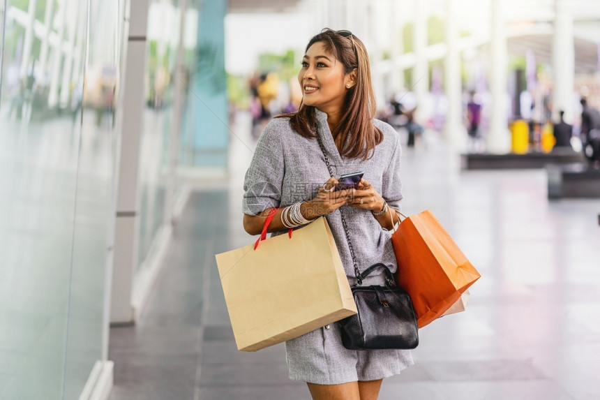 购物者曼谷女士亚洲使用智能手机检查在线购物订单与市中心商店修鞋和时尚概念的玻璃杯旁边衣服一起检查线上购物订单校对Portnoy图片