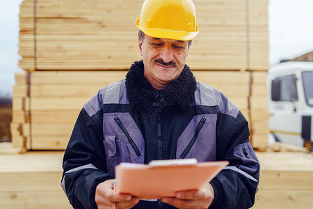 高级工程师证书专业的Caucasian高级男子建筑工一般人建筑承包商的肖像他们身着黄色保护头盔手持钢笔和现场数据报告项目文件核对检查男人行业背景